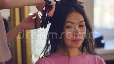 专业的发型师，发型师，梳着一个美丽模特的头发，有着亚洲的外表。 美容美发护理
